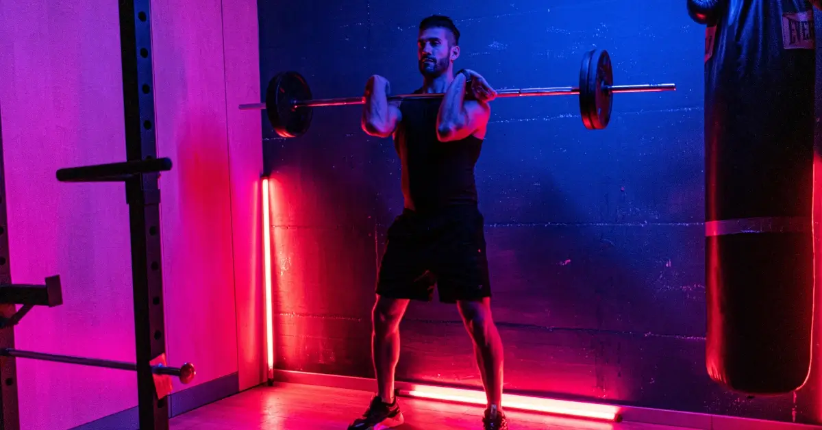 Man frontsquatting in front of red LED lights