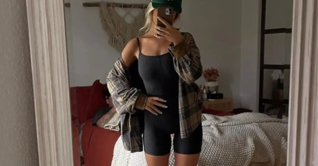 Woman in a short gym leggins and a flannel shirt taking a selfie 